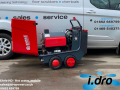 A red Ehrle HD pressure washer, with its hood up, standing in front of an Idro Power van.